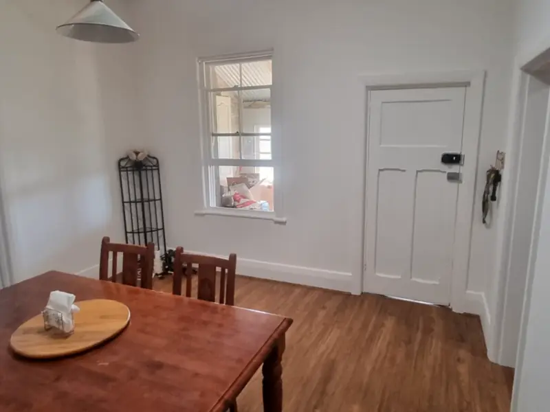 A dining room with a timber table, a sash window and a timber floor