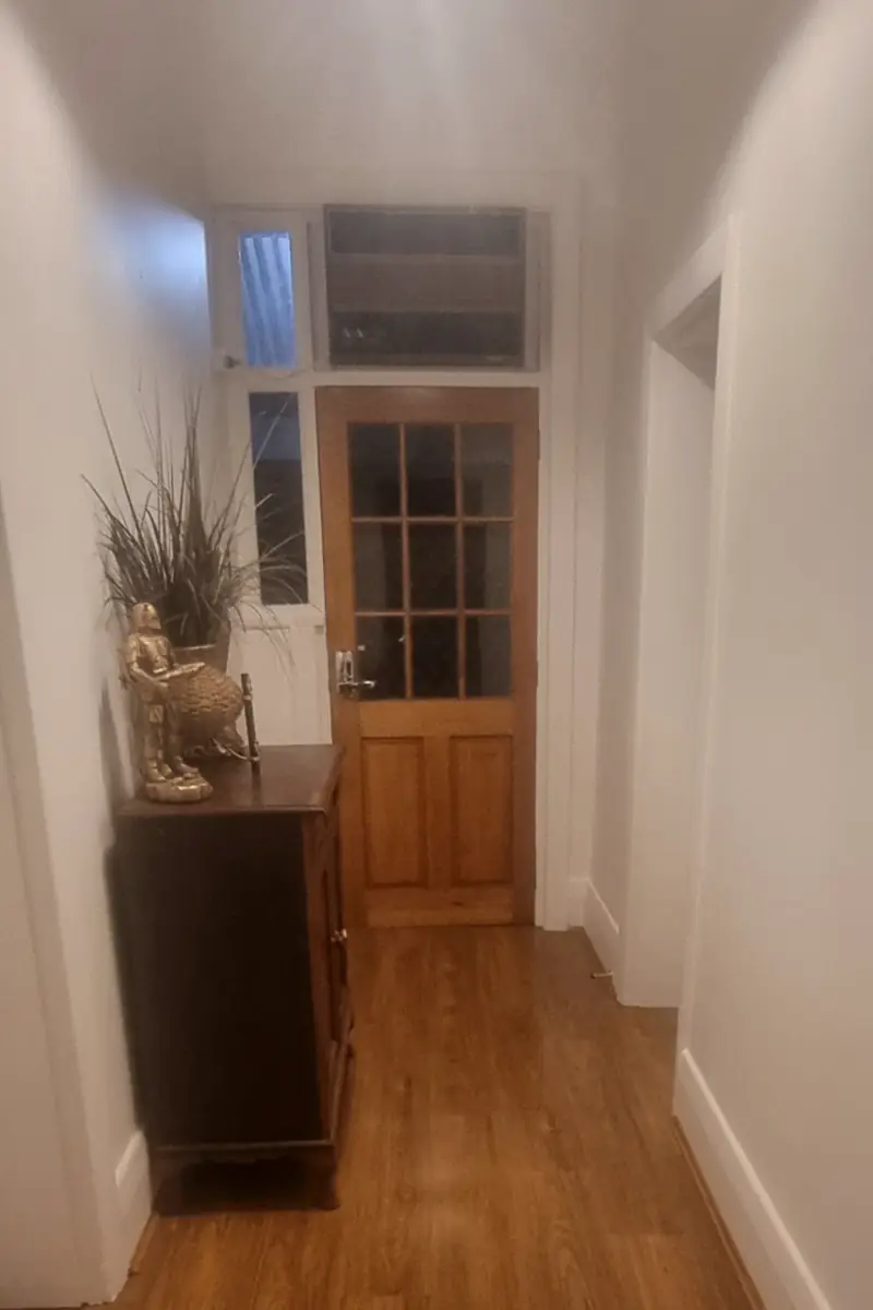 The same hallway finished: fresh paint, a polished timber floor, and the old glazed door and transom