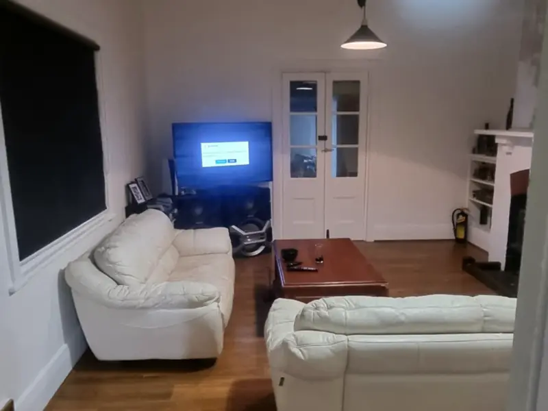 A finished lounge with white leather sofas and a polished timber floor