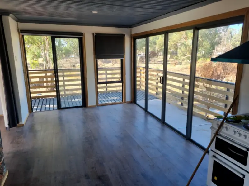 A bright room with a new timber-look floor and a wall of sliding doors opening onto a timber-slat balcony