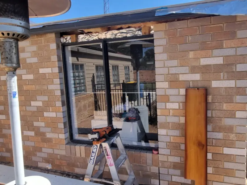A new window being set into a brick wall, with a stepladder in front