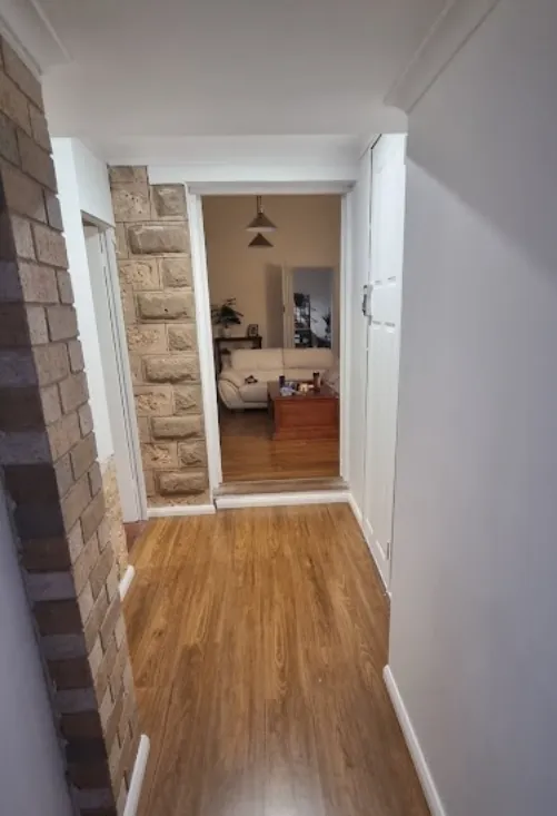 Timber-floored hallway with exposed brick feature