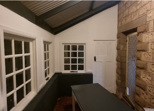 Room with restored sandstone feature wall and timber windows