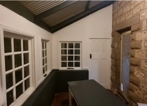 Room with restored sandstone feature wall and timber windows